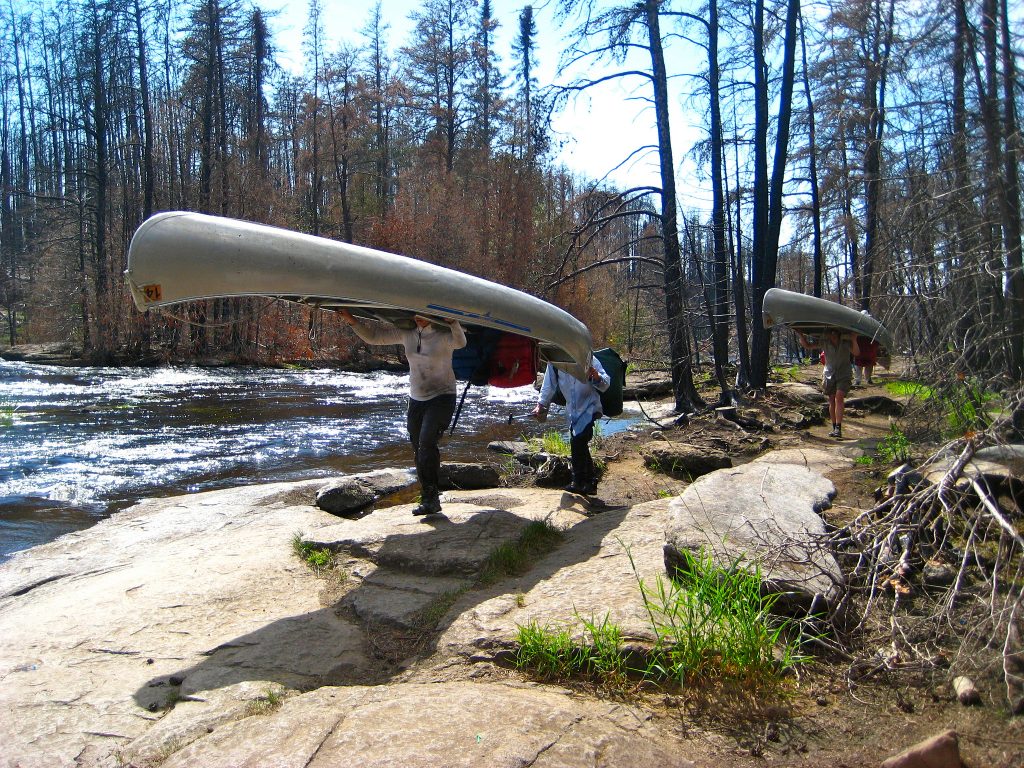 Students portage their canoes on a course in the Boundary Waters wilderness in Minnesota. Photo by Asa Fields.