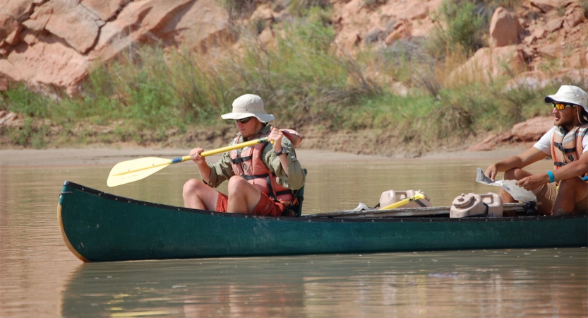 two people paddle a canoe on calm water.