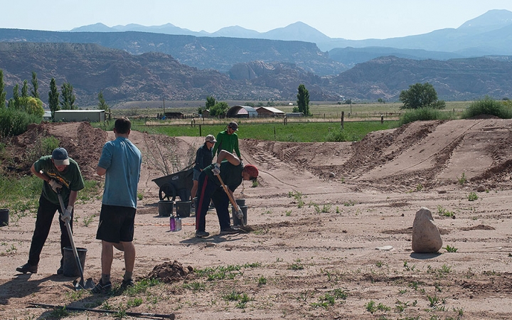 Students use shovels and wheelbarrows during a service project with outward bound.