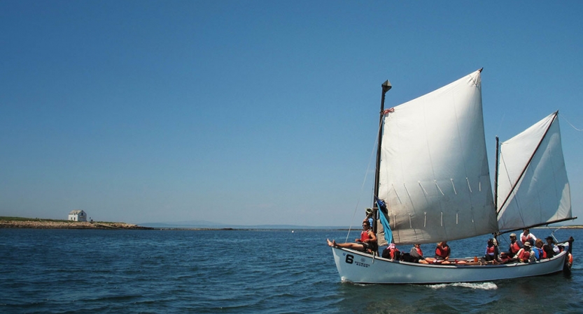 A sailboat full of people glides through the water