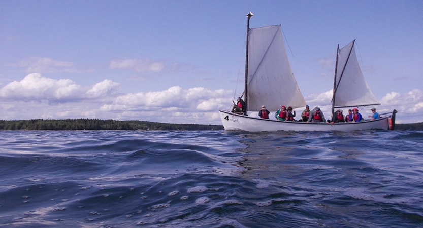 A sailboat holding a group of people floats on the water.