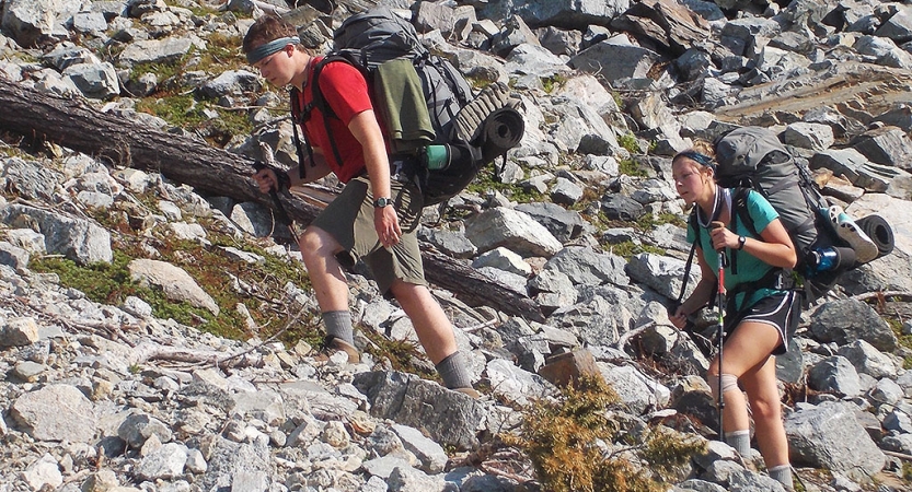 two people make their way up a rocky landscape on an outward bound trip
