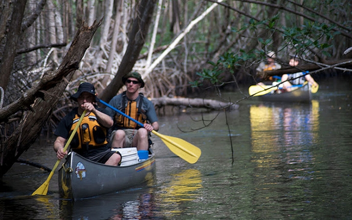 a group of people paddle canoes on an outward bound expedition 