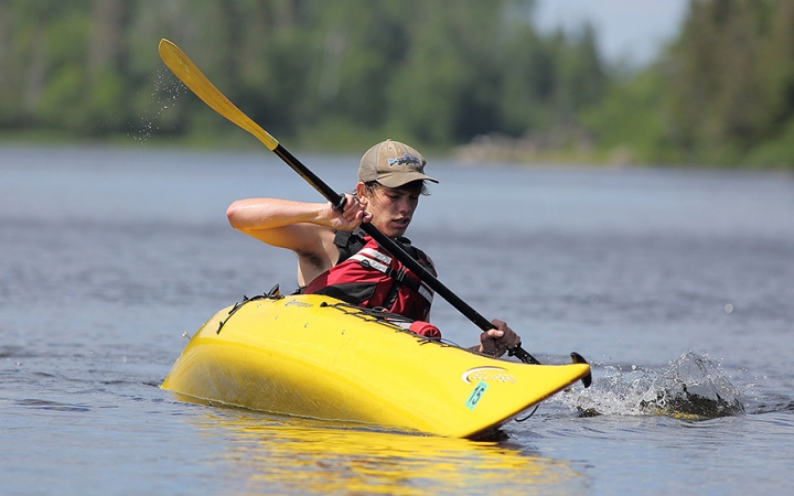 A person appears to practice a wet exit in a yellow kayak on a body of water. 