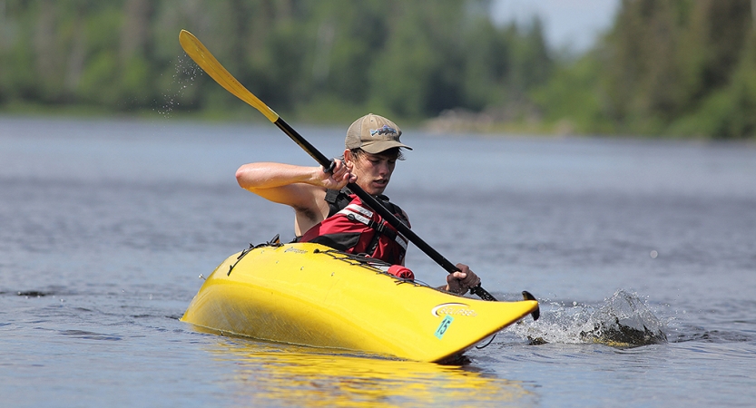 A person appears to practice a wet exit in a yellow kayak on a body of water. 