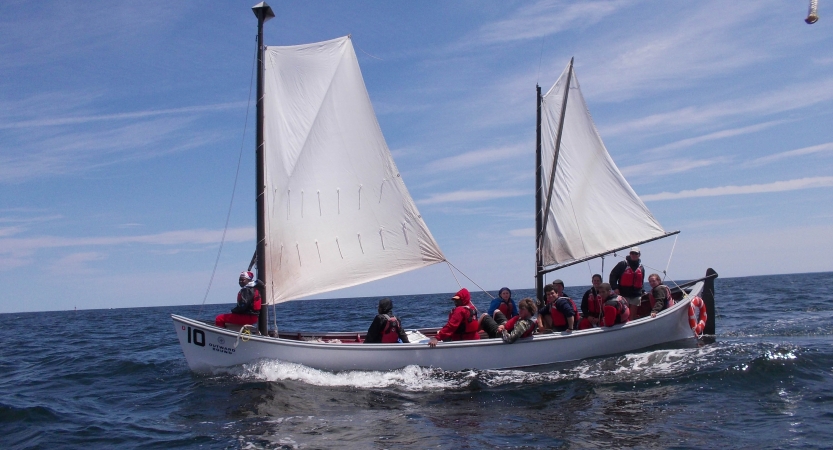 A sailboat full of people glides through the water